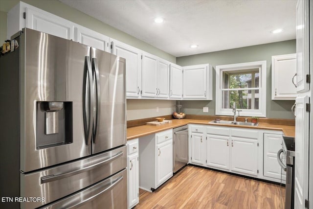 kitchen featuring white cabinetry, sink, stainless steel appliances, and light wood-type flooring