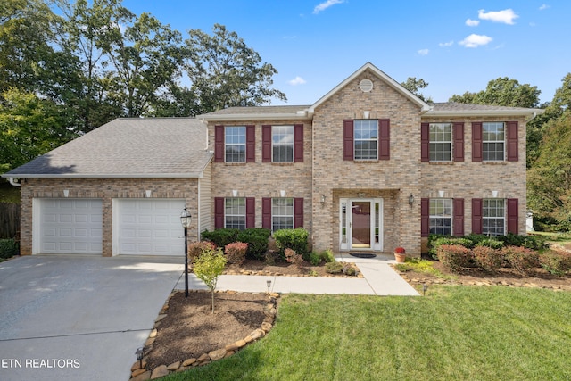 colonial home featuring a garage and a front lawn