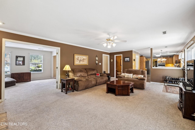 living room with crown molding, ceiling fan with notable chandelier, and light colored carpet