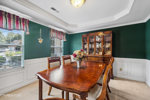 dining area featuring a tray ceiling, light colored carpet, and crown molding