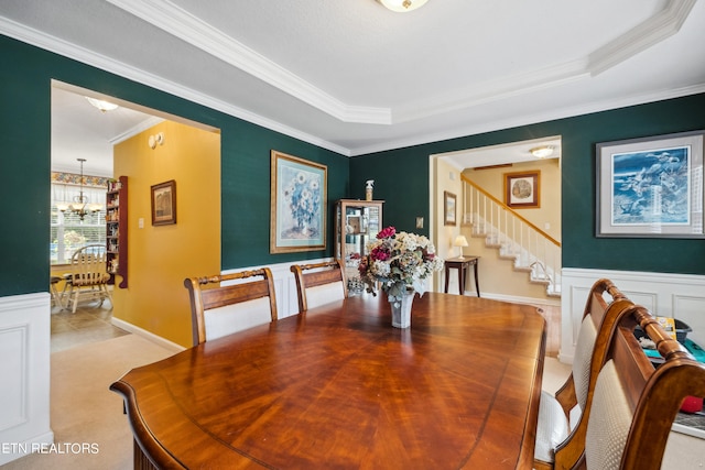 dining area with crown molding, a tray ceiling, an inviting chandelier, and light carpet