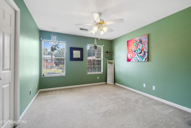 carpeted empty room with ceiling fan with notable chandelier