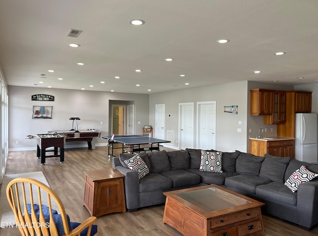 living room with light wood-type flooring, pool table, and indoor wet bar