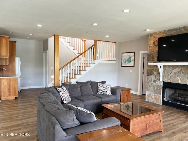 living room with hardwood / wood-style flooring, sink, and a fireplace