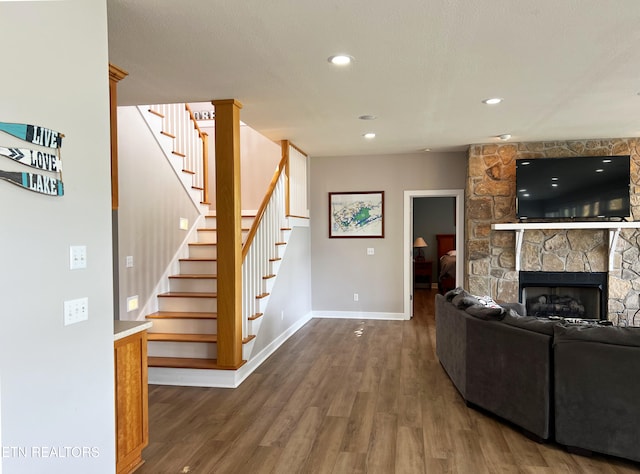 living room featuring a stone fireplace and dark hardwood / wood-style flooring