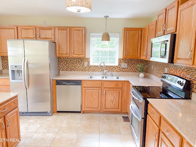 kitchen featuring pendant lighting, sink, appliances with stainless steel finishes, light stone counters, and decorative backsplash