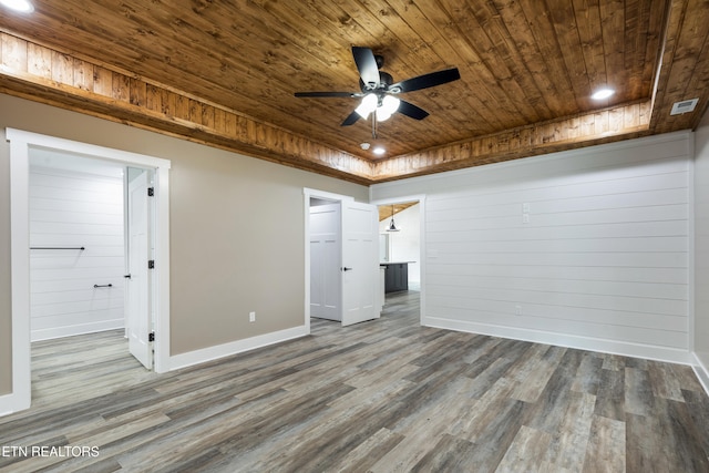 spare room with wood walls, a raised ceiling, hardwood / wood-style flooring, ceiling fan, and wood ceiling