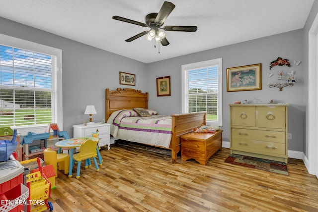 bedroom with ceiling fan, a textured ceiling, and light hardwood / wood-style flooring