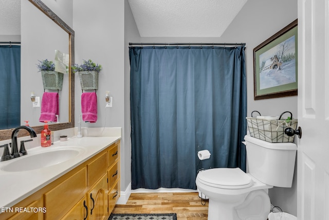 bathroom with hardwood / wood-style floors, vanity, toilet, and a textured ceiling