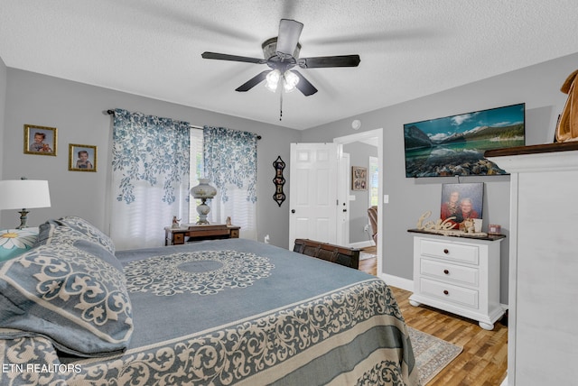 bedroom featuring ceiling fan, light wood-type flooring, and a textured ceiling