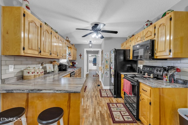 kitchen featuring black appliances, light wood-type flooring, a textured ceiling, tasteful backsplash, and kitchen peninsula