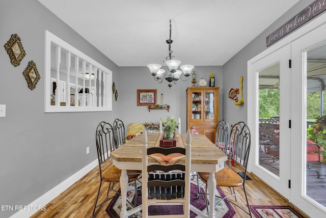 dining room with a notable chandelier, light hardwood / wood-style floors, and a textured ceiling