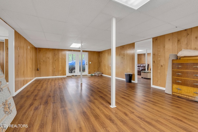 basement with hardwood / wood-style flooring, a drop ceiling, and wooden walls