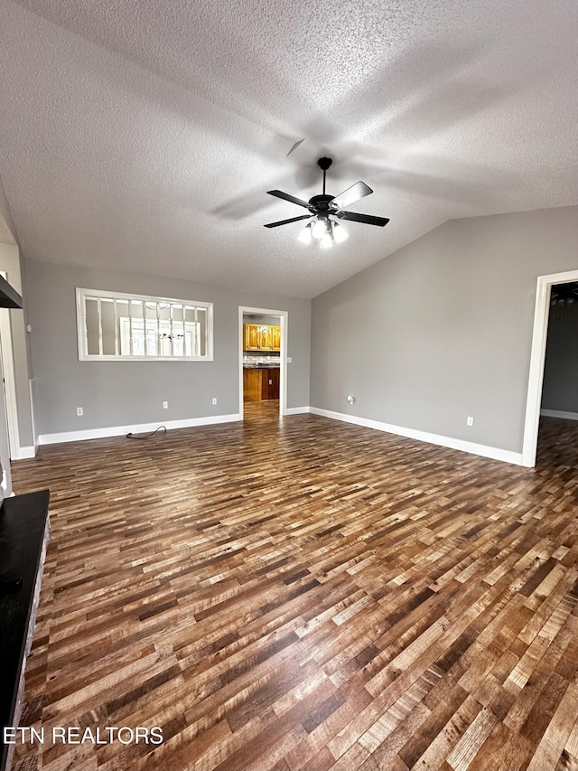 unfurnished living room with a textured ceiling, ceiling fan, dark wood-type flooring, and vaulted ceiling