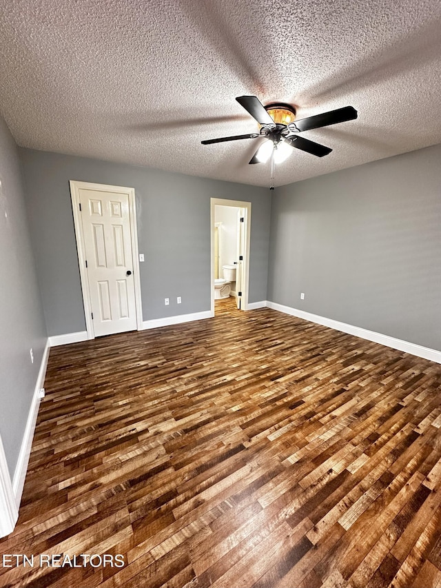 unfurnished bedroom featuring a textured ceiling, connected bathroom, ceiling fan, and dark hardwood / wood-style floors