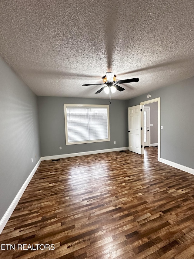 unfurnished room with ceiling fan, dark hardwood / wood-style flooring, and a textured ceiling