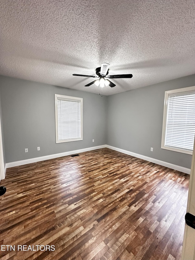 unfurnished room with ceiling fan, dark wood-type flooring, and a textured ceiling