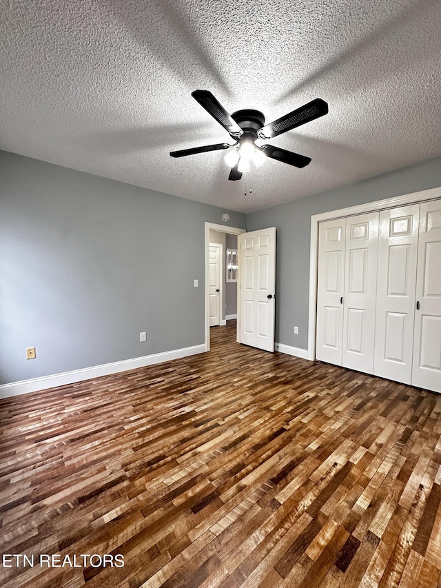 unfurnished bedroom with a textured ceiling, a closet, hardwood / wood-style flooring, and ceiling fan