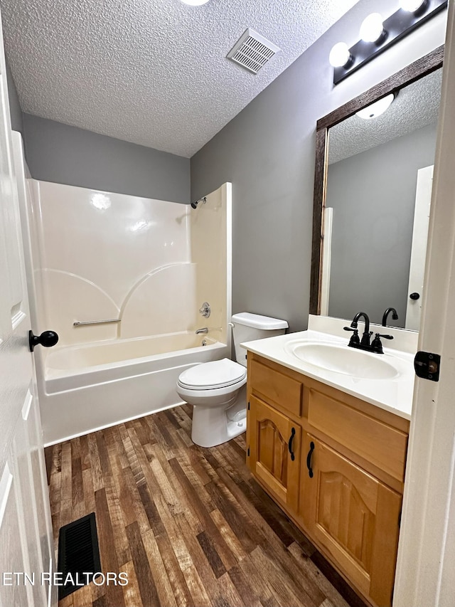 full bathroom featuring vanity, bathtub / shower combination, toilet, a textured ceiling, and wood-type flooring