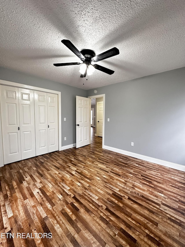 unfurnished bedroom with wood-type flooring, a textured ceiling, a closet, and ceiling fan