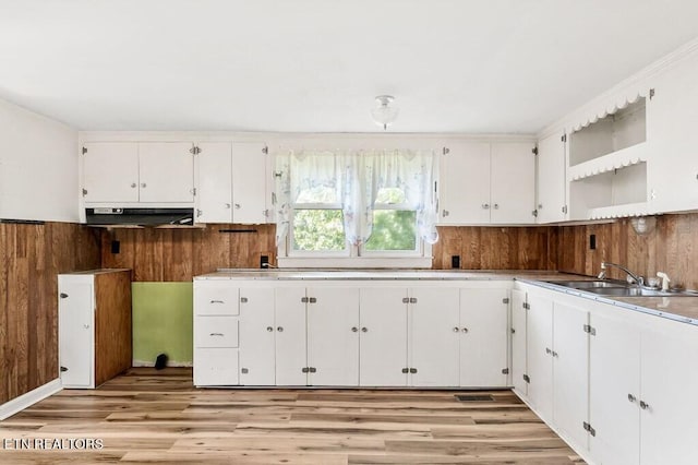 kitchen featuring white cabinets, wooden walls, light hardwood / wood-style floors, and sink