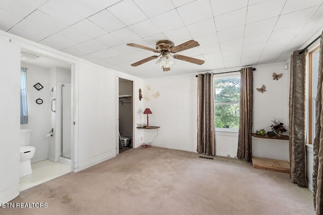 unfurnished bedroom with a spacious closet, a closet, ceiling fan, ensuite bathroom, and light colored carpet