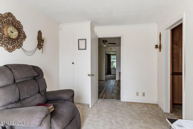 carpeted living room with crown molding and ceiling fan