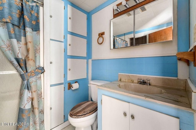 bathroom featuring tile walls, vanity, toilet, and a shower with shower curtain