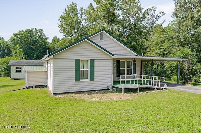 view of front of home featuring a shed, a carport, and a front lawn