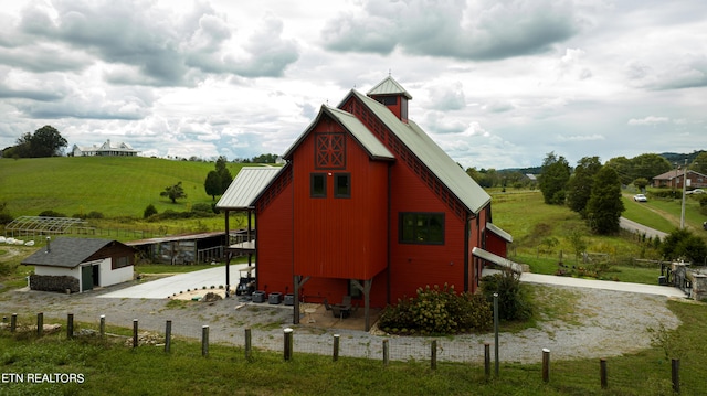 view of outbuilding featuring a rural view and a lawn