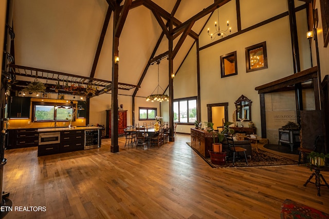 living room with hardwood / wood-style flooring, beamed ceiling, a wood stove, beverage cooler, and high vaulted ceiling