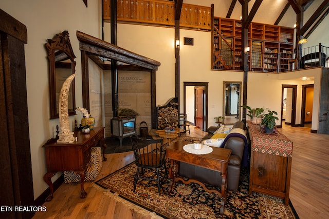 interior space featuring a wood stove, hardwood / wood-style floors, beamed ceiling, and a high ceiling