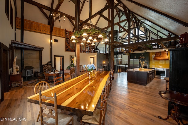 dining area featuring high vaulted ceiling, wood-type flooring, a textured ceiling, and beamed ceiling