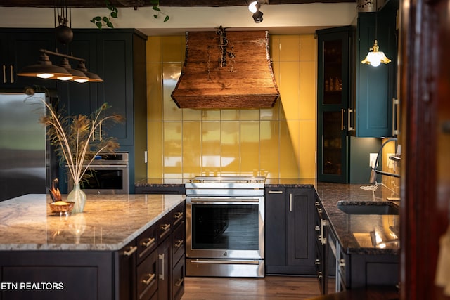 kitchen with exhaust hood, dark stone countertops, sink, decorative light fixtures, and stainless steel electric range oven