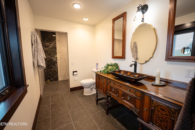 bathroom with vanity, tiled shower, toilet, and tile patterned floors