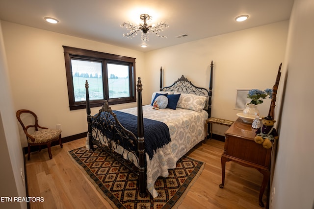 bedroom with light hardwood / wood-style floors and an inviting chandelier