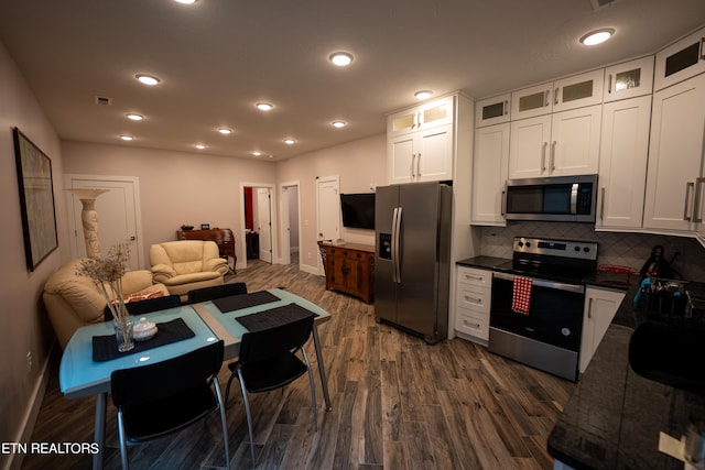 kitchen with appliances with stainless steel finishes, dark hardwood / wood-style flooring, decorative backsplash, and white cabinets