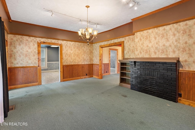 unfurnished living room with a textured ceiling, wooden walls, a notable chandelier, and rail lighting