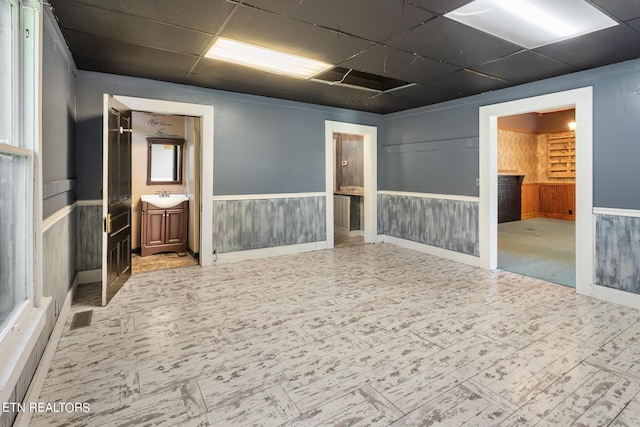 spare room with a paneled ceiling, wooden walls, and sink