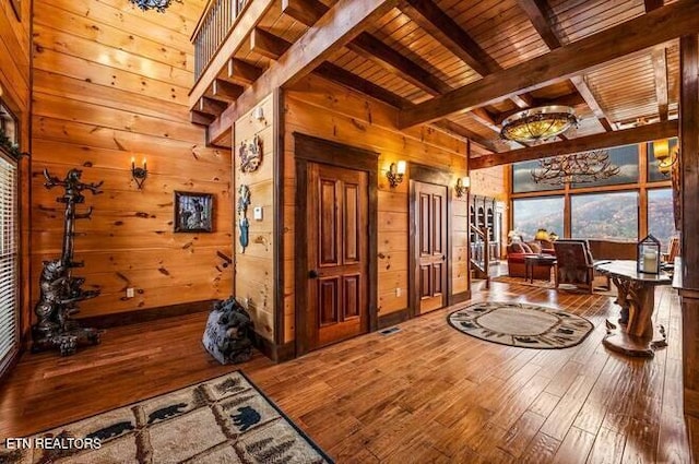 interior space featuring beam ceiling, wood walls, wood ceiling, and hardwood / wood-style flooring