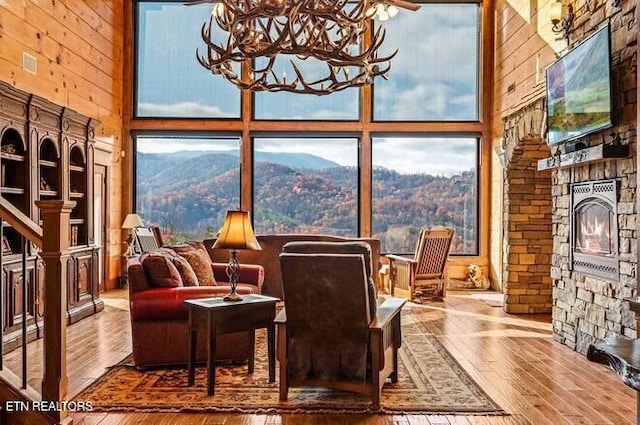 sitting room with a fireplace, wood-type flooring, a towering ceiling, and ceiling fan