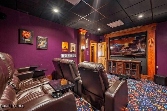 home theater room with carpet flooring, a drop ceiling, and decorative columns