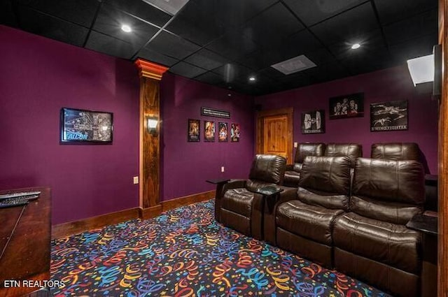 cinema room with carpet floors, ornate columns, and a drop ceiling