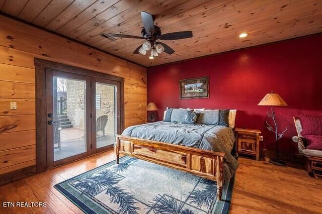 bedroom featuring hardwood / wood-style floors, wood walls, access to outside, ceiling fan, and wood ceiling