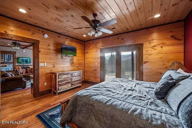 bedroom with hardwood / wood-style flooring, ceiling fan, and wood walls