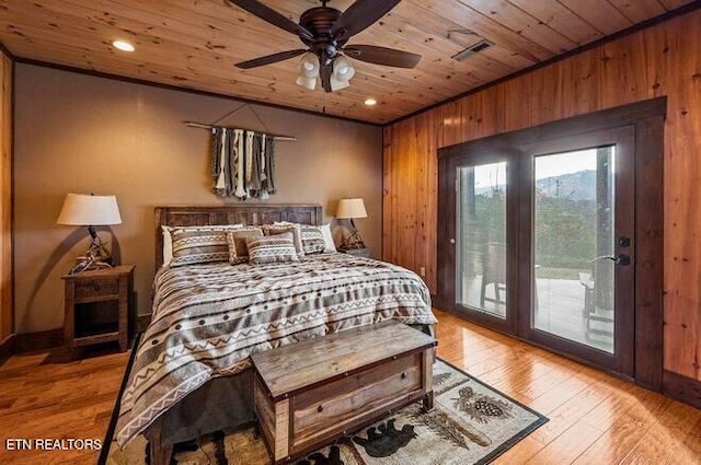 bedroom with ceiling fan, wood walls, access to exterior, and light wood-type flooring