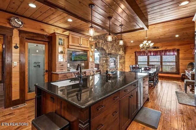 kitchen featuring hardwood / wood-style floors, wood walls, wooden ceiling, hanging light fixtures, and a large island