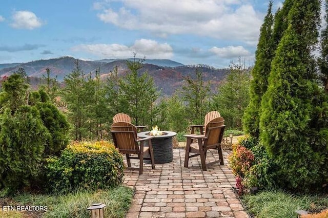 view of patio with a mountain view and an outdoor fire pit