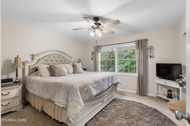 bedroom featuring ceiling fan, light colored carpet, and a textured ceiling