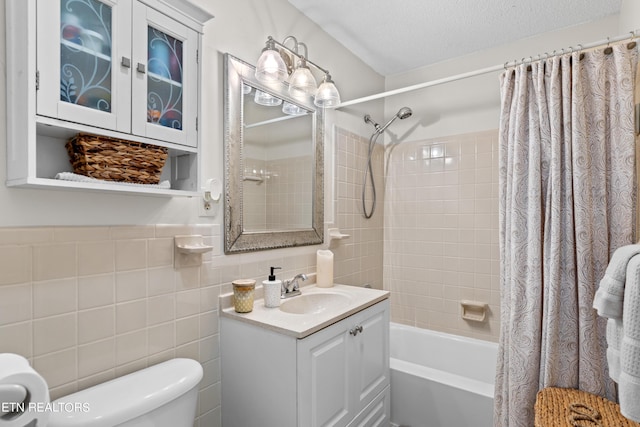 full bathroom featuring tile walls, shower / bath combo with shower curtain, vanity, a textured ceiling, and toilet